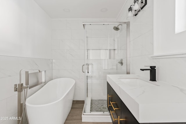 bathroom with tile walls, plus walk in shower, vanity, and wood-type flooring