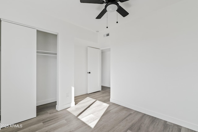 unfurnished bedroom with light wood-type flooring, ceiling fan, and a closet