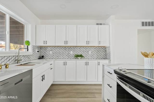 kitchen with white cabinets, light stone countertops, dishwasher, and sink