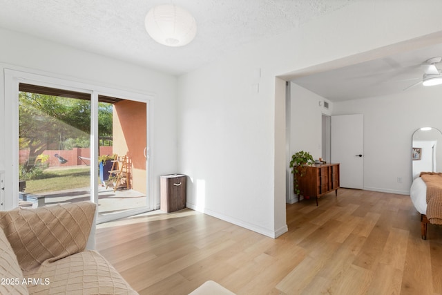 living room featuring a textured ceiling, ceiling fan, and light hardwood / wood-style flooring