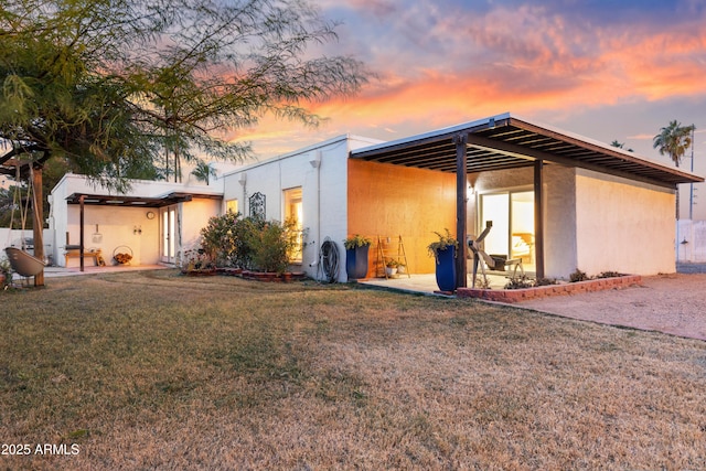 back house at dusk featuring a yard