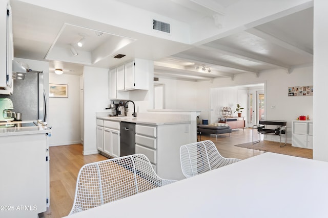 kitchen with sink, appliances with stainless steel finishes, white cabinetry, light hardwood / wood-style floors, and beam ceiling