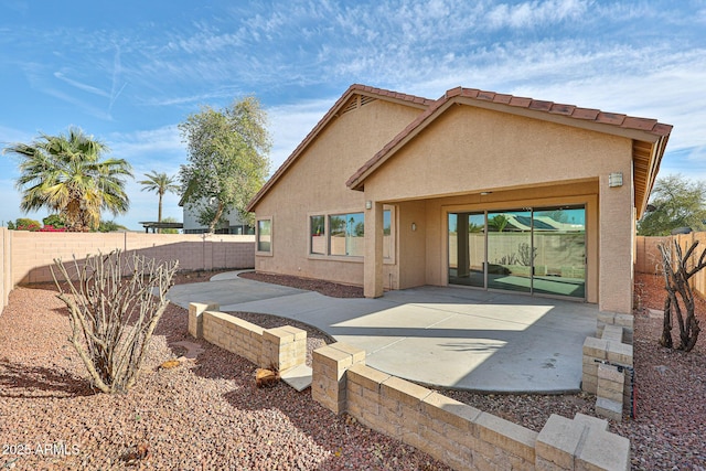 rear view of house with a tiled roof, a patio area, a fenced backyard, and stucco siding