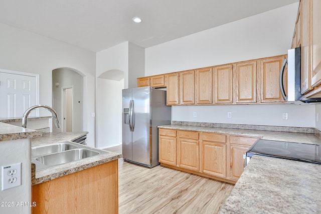 kitchen with appliances with stainless steel finishes, light wood-type flooring, light countertops, and a sink