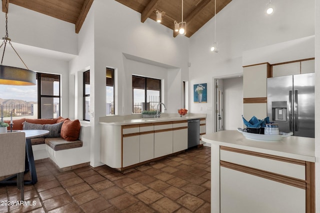 kitchen featuring beam ceiling, pendant lighting, stainless steel appliances, and wooden ceiling