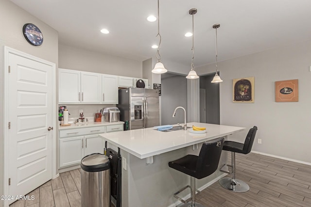 kitchen with a center island with sink, decorative light fixtures, white cabinets, and stainless steel refrigerator with ice dispenser