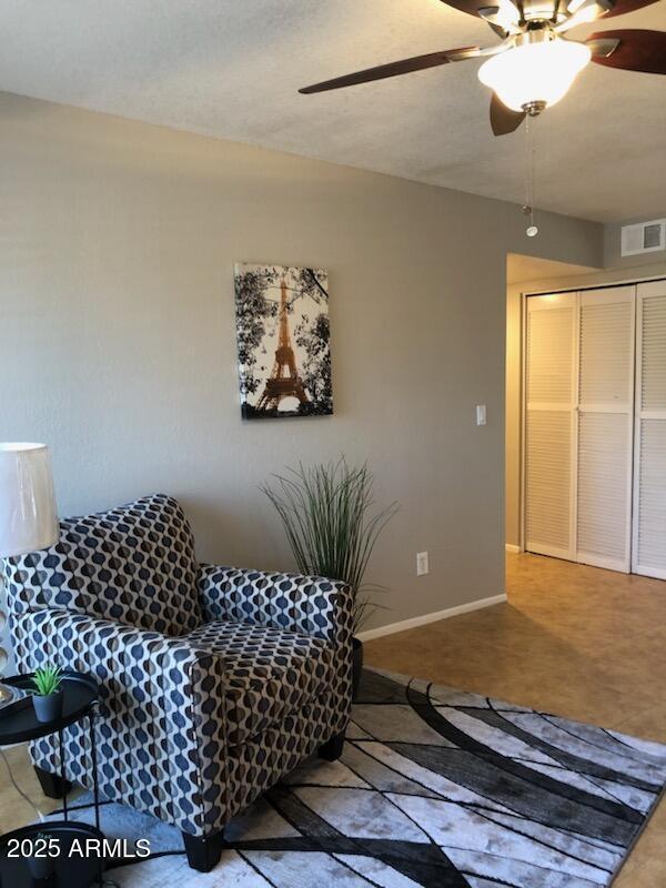 living room featuring ceiling fan, visible vents, and baseboards