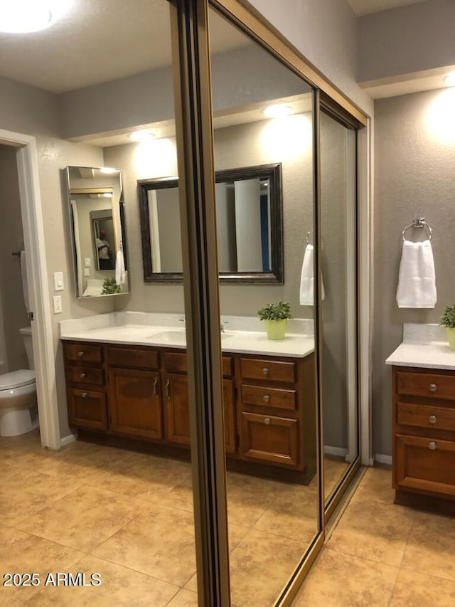 full bath featuring toilet, vanity, and tile patterned floors