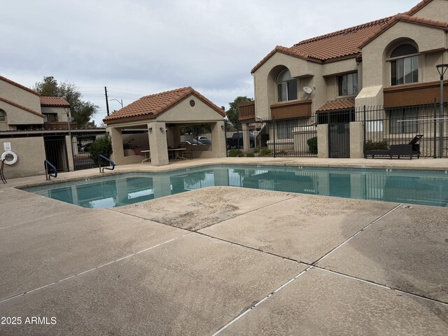 pool with a patio area and fence