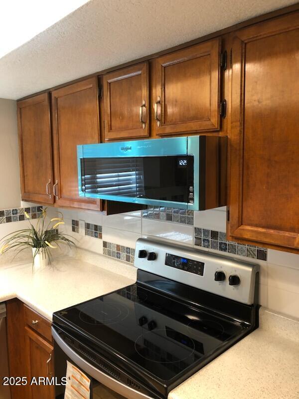 kitchen with stainless steel appliances, tasteful backsplash, and light countertops