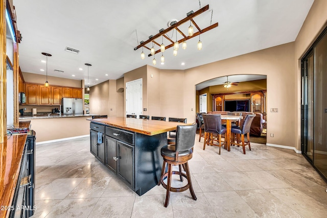 747 E Meadow Ln, Phoenix, AZ 85022 - kitchen with a breakfast bar area, visible vents, arched walkways, a center island, and stainless steel fridge