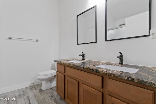 full bathroom with double vanity, wood finished floors, a sink, and toilet