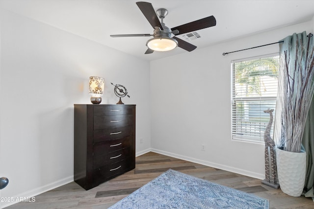 bedroom with baseboards, visible vents, ceiling fan, and wood finished floors