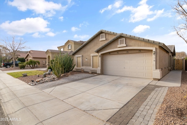 view of front of property featuring a garage, fence, concrete driveway, and stucco siding