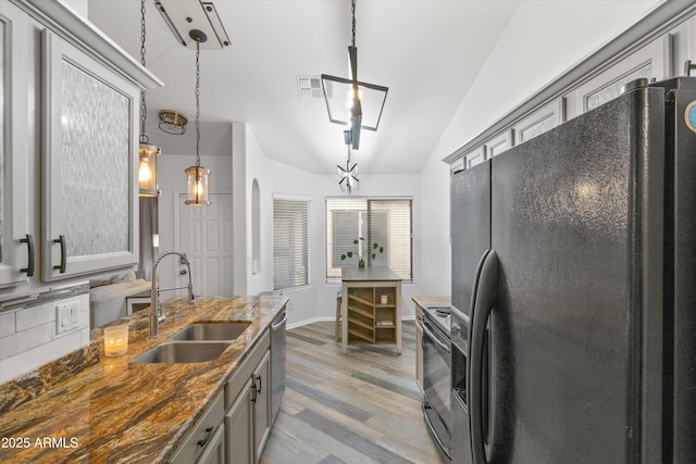 kitchen featuring arched walkways, light wood-style flooring, a sink, gray cabinets, and black appliances