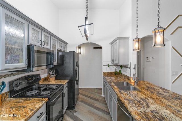 kitchen featuring appliances with stainless steel finishes, arched walkways, a sink, and gray cabinetry