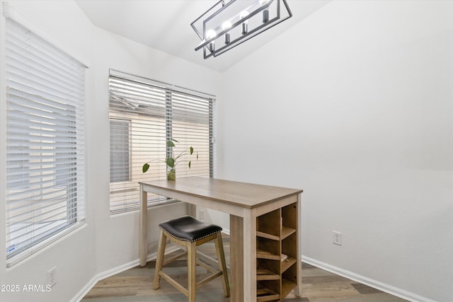 dining room with lofted ceiling, baseboards, and wood finished floors