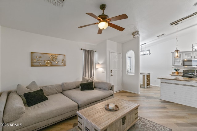 living room with vaulted ceiling, ceiling fan, light wood-type flooring, and visible vents