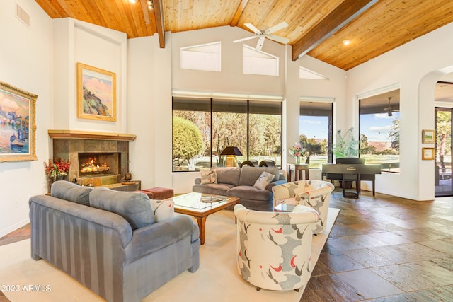 living room featuring beamed ceiling, ceiling fan, wooden ceiling, a fireplace, and high vaulted ceiling