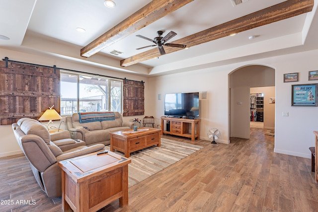 living area featuring arched walkways, visible vents, baseboards, and wood finished floors