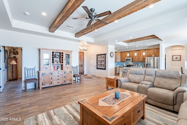 living area with recessed lighting, visible vents, light wood-style floors, a tray ceiling, and beamed ceiling