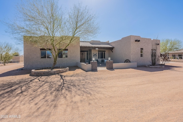 rear view of house with a patio, a tiled roof, and stucco siding