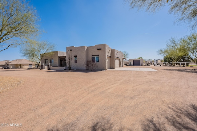 rear view of house featuring an attached garage, concrete driveway, and stucco siding