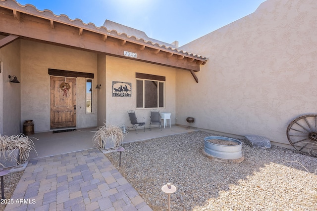 entrance to property featuring a patio area and stucco siding