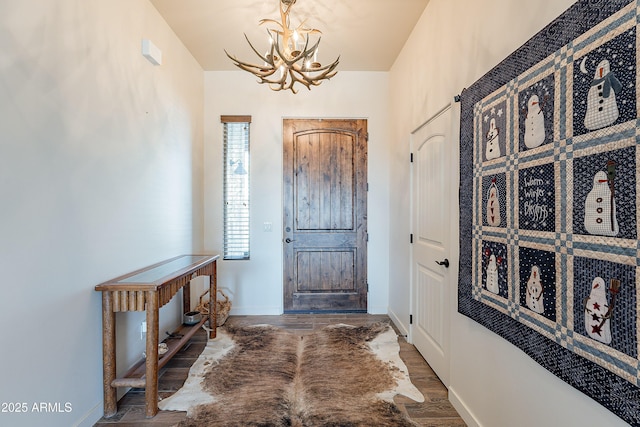 entrance foyer featuring a chandelier, baseboards, and wood finished floors