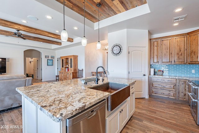 kitchen with arched walkways, stainless steel appliances, visible vents, a sink, and wood finished floors