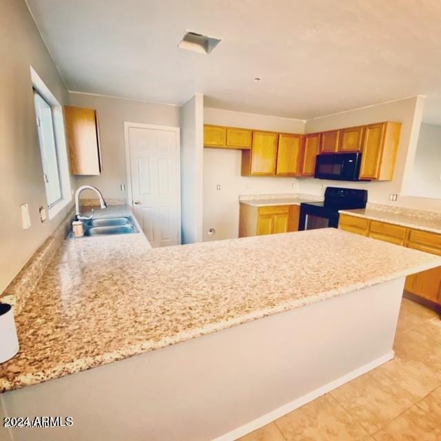 kitchen with light tile patterned flooring, black appliances, sink, and kitchen peninsula