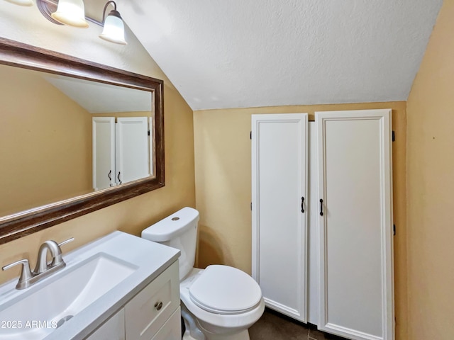 bathroom featuring vanity, vaulted ceiling, a textured ceiling, and toilet