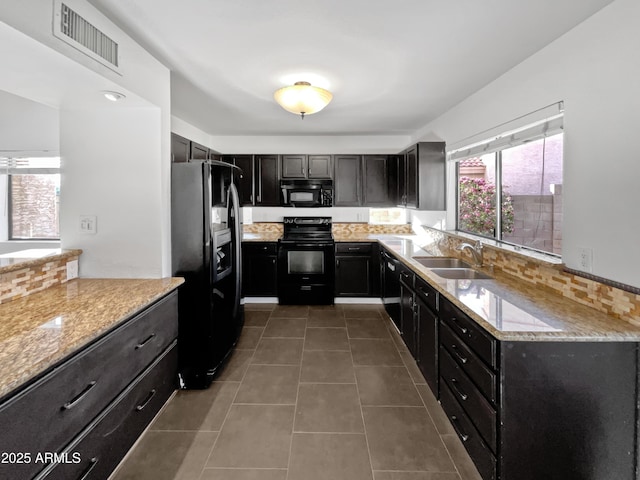 kitchen featuring sink, tile patterned floors, black appliances, and light stone countertops