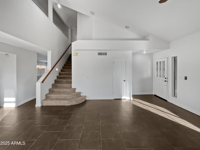 entryway with dark tile patterned flooring and high vaulted ceiling