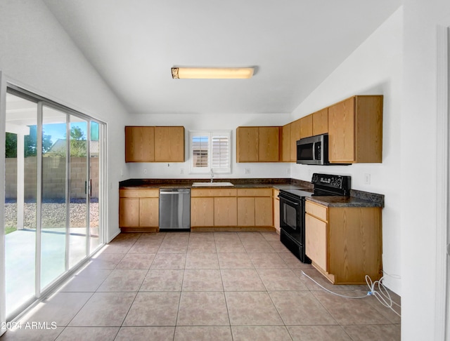 kitchen featuring sink, light tile patterned floors, appliances with stainless steel finishes, and lofted ceiling