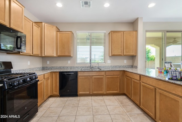 kitchen featuring light tile patterned floors, light stone countertops, sink, and black appliances