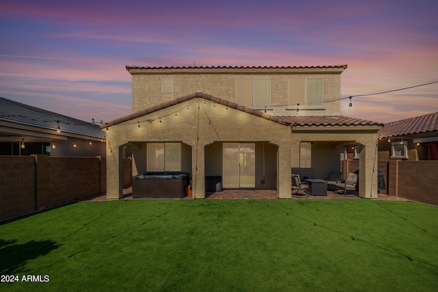 back house at dusk with a yard and a patio