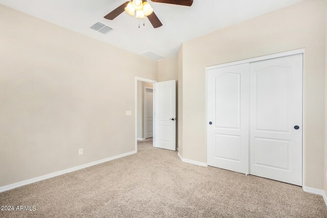 unfurnished bedroom featuring ceiling fan, a closet, and light colored carpet