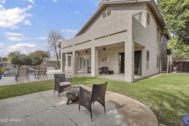 back of house featuring a fire pit, a patio area, ceiling fan, and a lawn