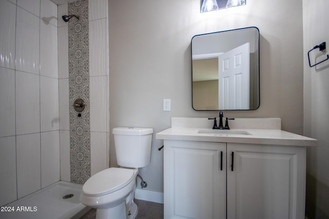 bathroom featuring a tile shower, vanity, and toilet