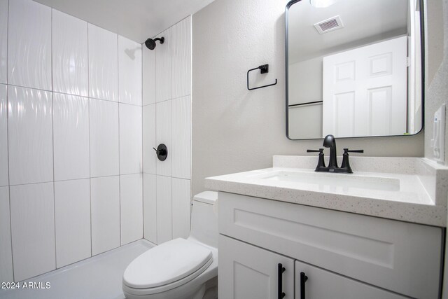 bathroom with vanity, toilet, and tiled shower