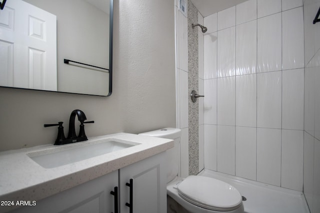 bathroom featuring tiled shower, vanity, and toilet