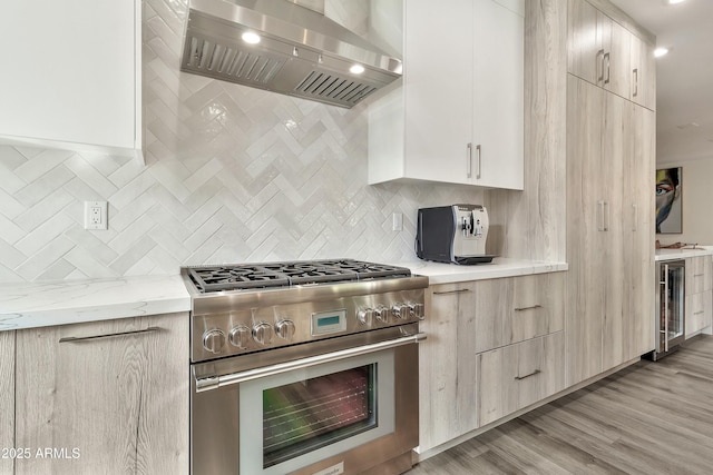 kitchen featuring range hood, backsplash, high end range, and wine cooler