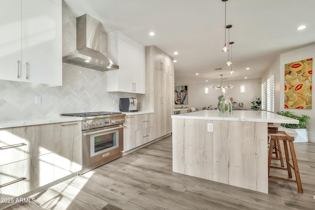 kitchen with light countertops, wall chimney exhaust hood, modern cabinets, and high end range