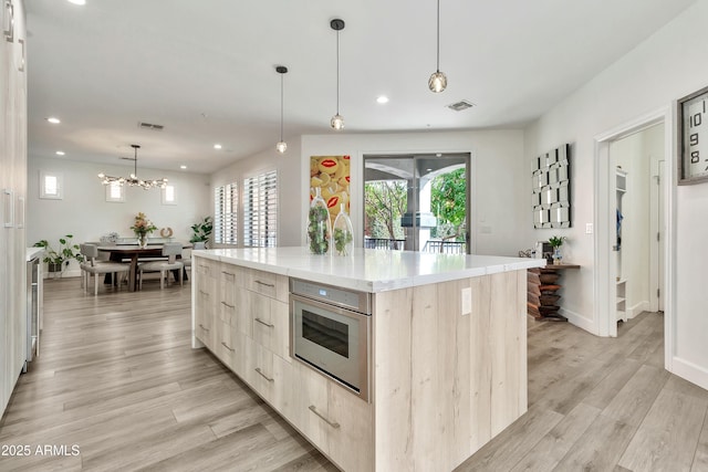 kitchen featuring a large island, modern cabinets, light brown cabinets, and visible vents