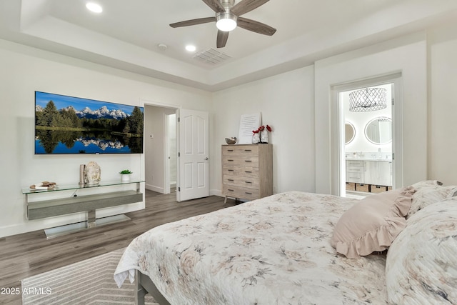 bedroom with recessed lighting, dark wood-type flooring, visible vents, baseboards, and a tray ceiling