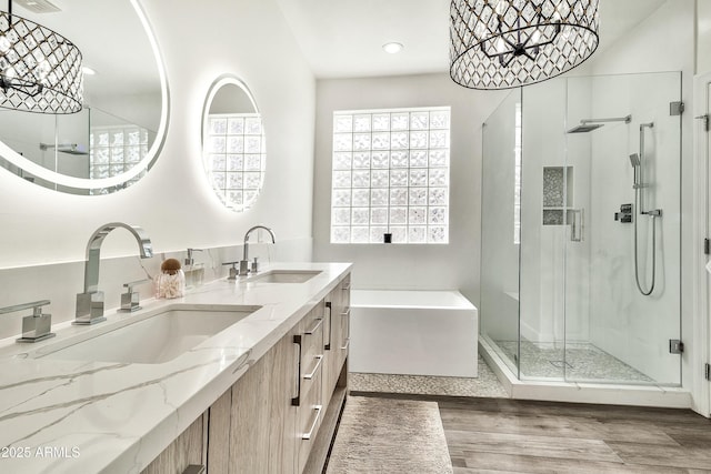 full bathroom featuring a garden tub, double vanity, wood finished floors, and a sink