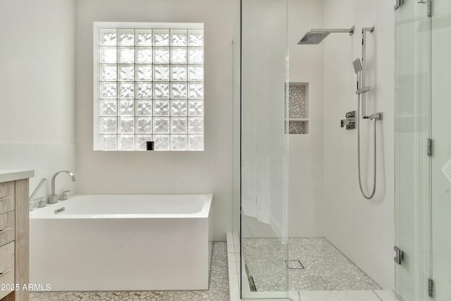 bathroom featuring a stall shower, a garden tub, and vanity