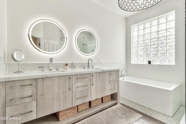 bathroom with double vanity, a soaking tub, and a sink