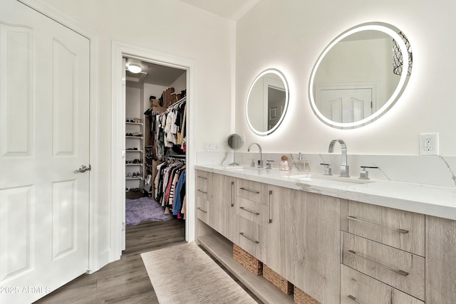 bathroom featuring double vanity, wood finished floors, and a sink